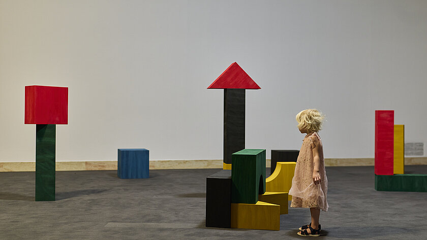 Kind in der Ausstellung, in der große bunte Bauklötze zu sehen sind.