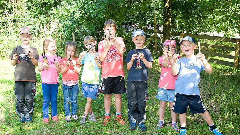 Kinder auf einer grünen Wiese mit Pinseln in den Händen.